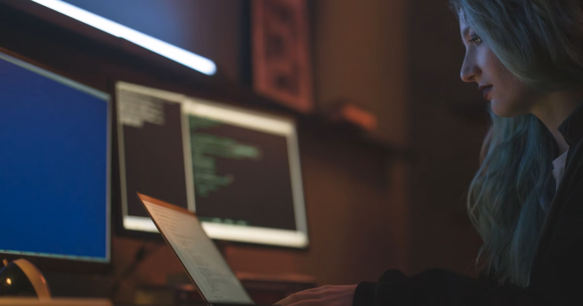 La trappola del debito tecnico generato dall'IA — stressed software developer looking at multiple computer monitors with code