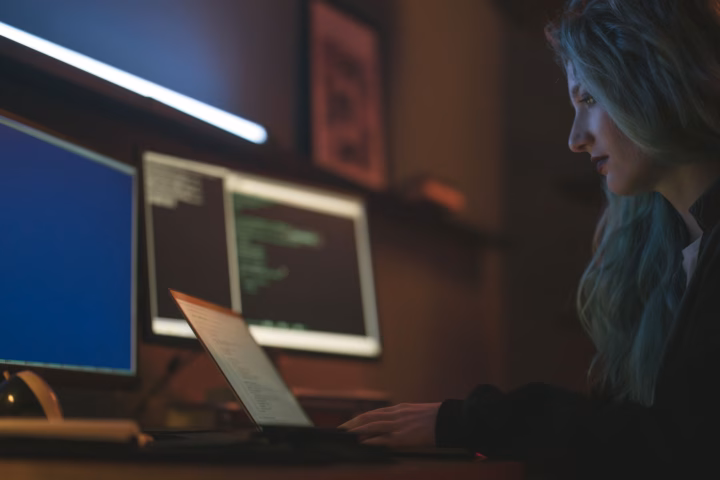 La trappola del debito tecnico generato dall'IA — stressed software developer looking at multiple computer monitors with code